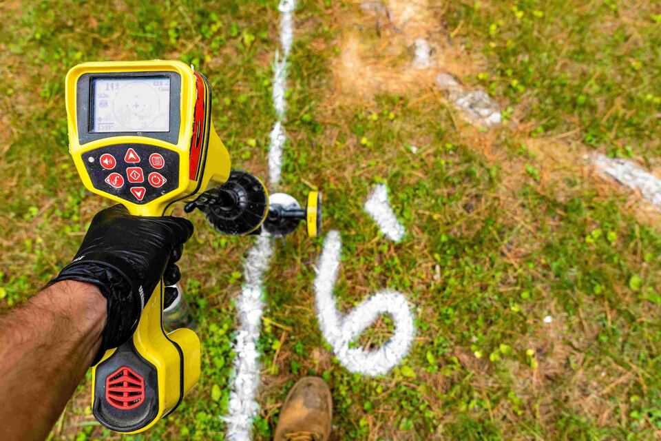 Pipe locator tracing a sewer line, with the route marked on the ground